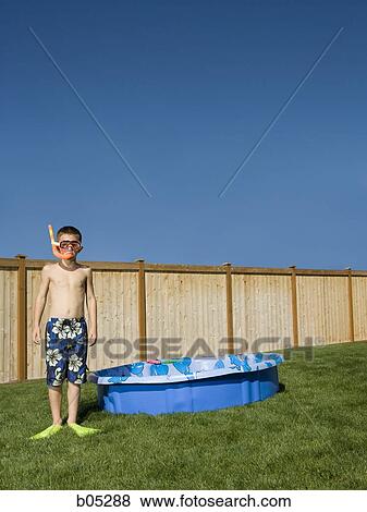 Stock Photo - Boy in swim trunks with flippers and snorkel in yard. Fotosearch