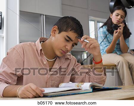 Boy studying at table with girl talking on phone View Large Photo Image Stock Image - Boy studying at table with girl talking on phone. Fotosearch