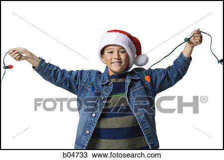 Stock Image - Boy with santa hat and Christmas lights. Fotosearch