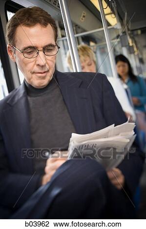 Stock Image - Businessman doing crossword on city bus or subway. Fotosearch