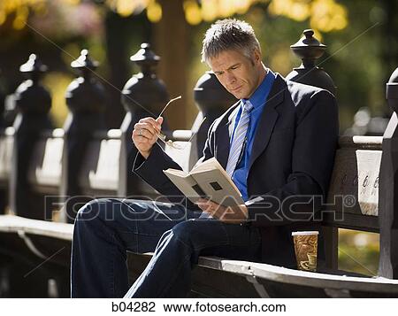 Businessman on wooden bench outdoors with book View Large Photo Image Stock Image - Businessman on wooden bench outdoors with book. Fotosearch