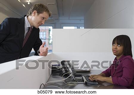 Businessman talking to woman in cubicle View Large Photo Image Stock Photo - Businessman talking to woman in cubicle. Fotosearch