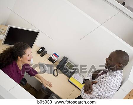 Businessman talking with woman in cubicle View Large Photo Image Stock Image - Businessman talking with woman in cubicle. Fotosearch