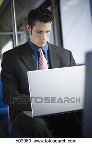 Stock Image - Businessman using laptop computer on city bus or subway. Fotosearch