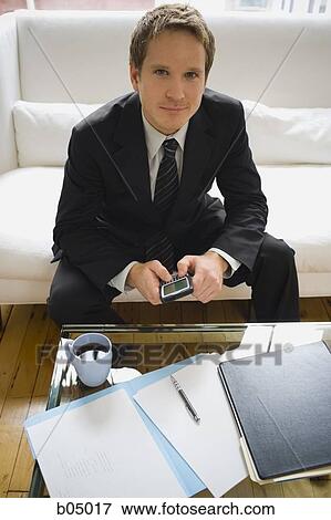 Stock Photo - Businessman with blackberry sitting on sofa. Fotosearch