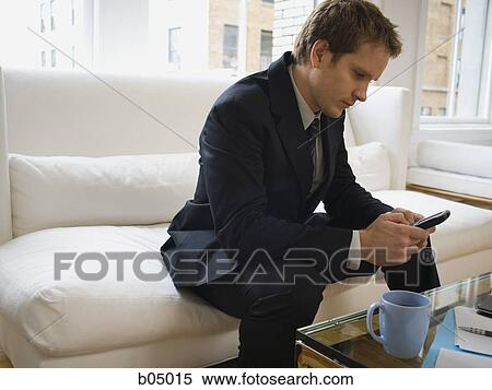 Stock Photography - Businessman with blackberry sitting on sofa. Fotosearch