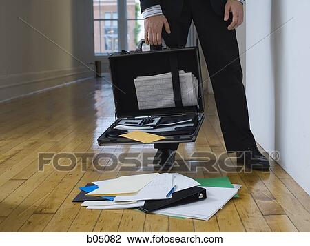Stock Image - Businessman with opened briefcase and contents on floor. Fotosearch