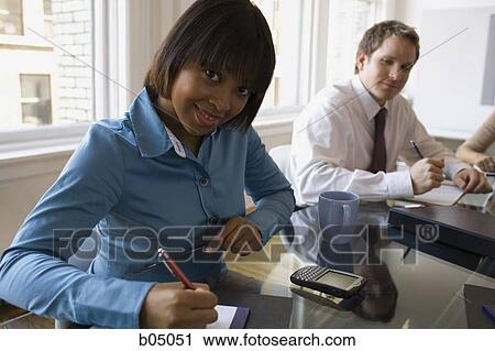 Stock Image - Businesswoman taking notes at meeting. Fotosearch
