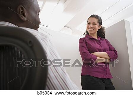 Businesswoman talking with man in cubicle View Large Photo Image Picture - Businesswoman talking with man in cubicle. Fotosearch