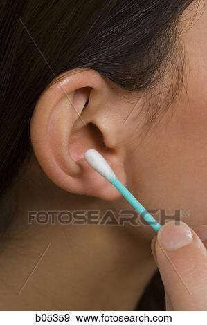 Stock Photo - Closeup of female ear with cotton swab. Fotosearch