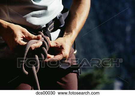 Stock Image - Closeup of hands tieing rope. Fotosearch