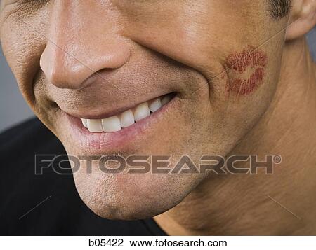 Stock Image - Closeup of man smiling with lipstick kiss on cheek. Fotosearch
