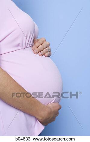 Stock Image - Closeup of pregnant woman holding belly. Fotosearch