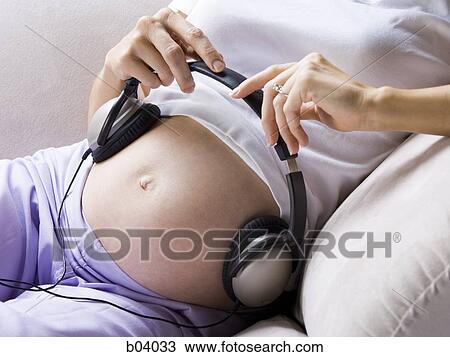 Closeup of pregnant woman sitting with headphones on belly View Large Photo Image Stock Image - Closeup of pregnant woman sitting with headphones on belly. Fotosearch
