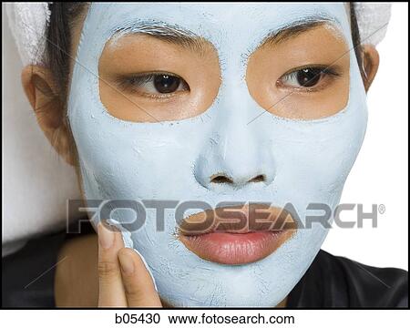 Stock Image - Closeup of woman applying facial mask. Fotosearch