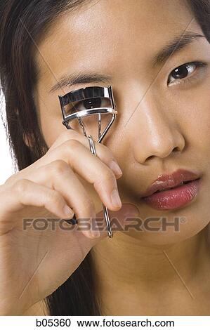 Closeup of woman curling eyelashes View Large Photo Image Stock Image - Closeup of woman curling eyelashes. Fotosearch