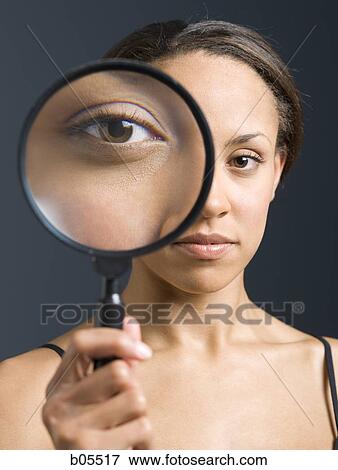 Closeup of woman holding magnifying glass to eye View Large Photo Image Stock Photo - Closeup of woman holding magnifying glass to eye. Fotosearch