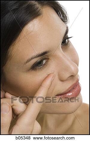 Stock Photo - Closeup of woman inserting contact lens. Fotosearch