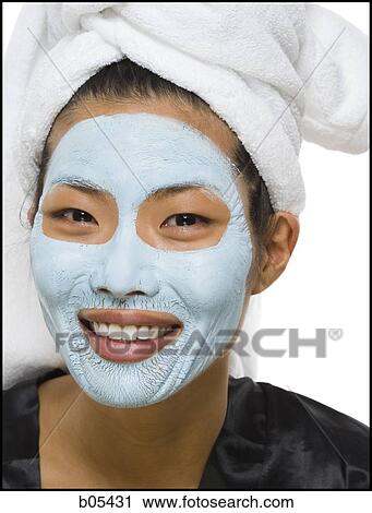 Stock Image - Closeup of woman smiling with facial mask and hair towel. Fotosearch