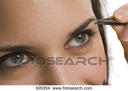 Closeup of woman tweezing eyebrows View Large Photo Image Picture - Closeup of woman tweezing eyebrows. Fotosearch