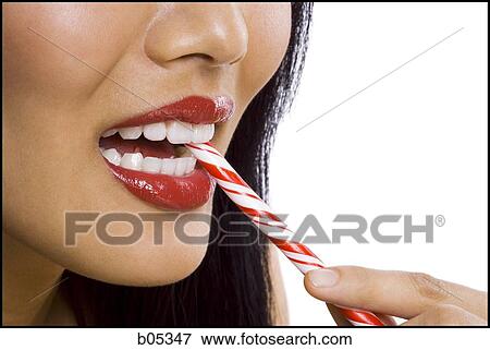 Closeup of woman with red lipstick eating candy cane View Large Photo Image Stock Photo - Closeup of woman with red lipstick eating candy cane. Fotosearch