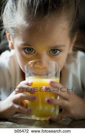 Stock Image - Closeup of young girl drinking orange juice. Fotosearch