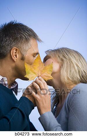 Couple kissing behind leaf View Large Photo Image Stock Image - Couple kissing behind leaf. Fotosearch