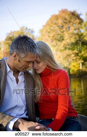 Couple sitting by water View Large Photo Image Stock Photo - Couple sitting by water. Fotosearch
