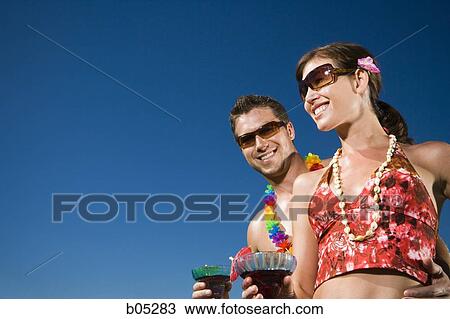 Couple with cocktails in swimsuits with blue sky View Large Photo Image Stock Image - Couple with cocktails in swimsuits with blue sky. Fotosearch