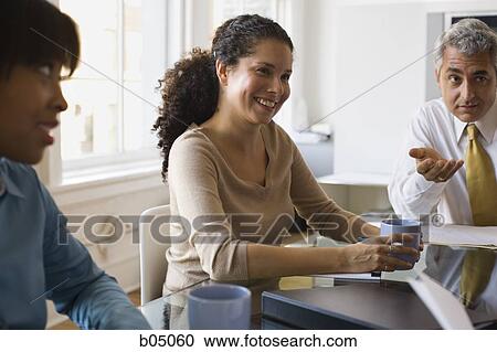Stock Image - Discussion at business meeting with three people. Fotosearch