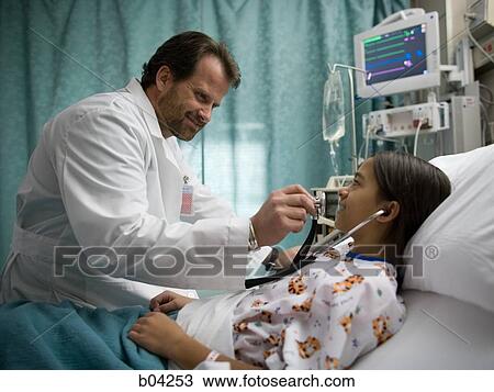 Stock Image - Doctor examining girl in hospital bed. Fotosearch