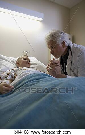Doctor sitting by young boy in hospital bed View Large Photo Image Stock Photo - Doctor sitting by young boy in hospital bed. Fotosearch