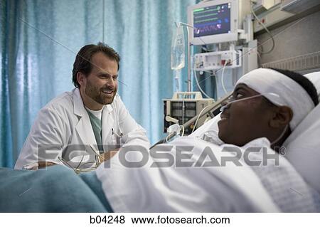 Doctor talking to boy in hospital bed View Large Photo Image Stock Photo - Doctor talking to boy in hospital bed. Fotosearch