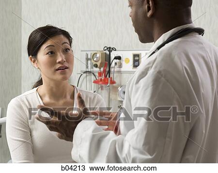 Doctor talking to woman in examining room View Large Photo Image Stock Image - Doctor talking to woman in examining room. Fotosearch