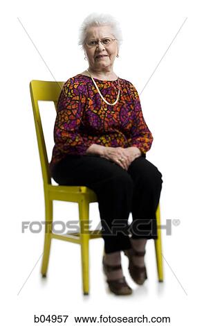 Stock Photo - Elderly woman sitting in yellow chair. Fotosearch