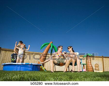 Family in yard with children's pool and cocktails View Large Photo Image Stock Image - Family in yard with children's pool and cocktails. Fotosearch