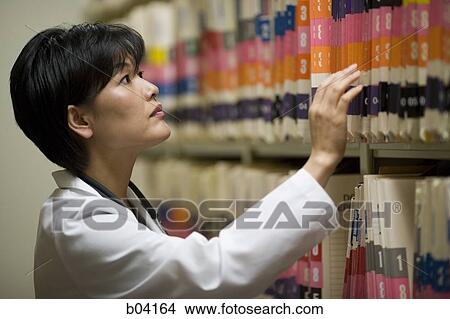 Picture - Female doctor looking at patient records. Fotosearch