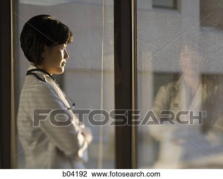 Female doctor looking through window View Large Photo Image Stock Image - Female doctor looking through window. Fotosearch