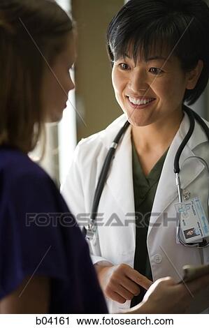 Female doctor smiling at nurse View Large Photo Image Stock Image - Female doctor smiling at nurse. Fotosearch