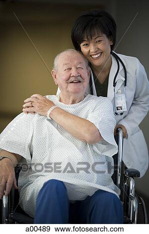 Stock Photo - Female doctor with mature man in wheelchair. Fotosearch