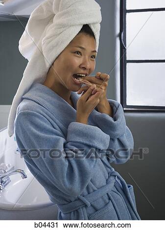 Stock Image - Female in bathroom flossing. Fotosearch