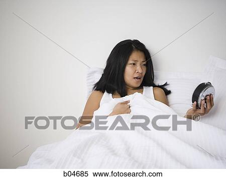 Stock Photography - Female in bed with alarm clock. Fotosearch