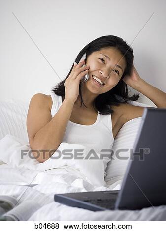 Female in bed with cell phone and laptop View Large Photo Image Stock Photo - Female in bed with cell phone and laptop. Fotosearch