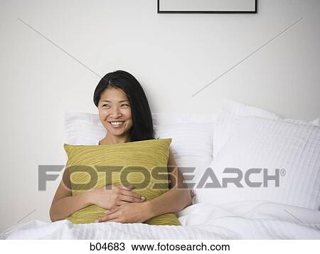 Stock Image - Female in bed with pillows. Fotosearch