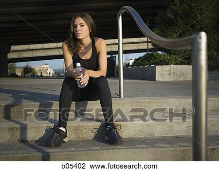 Female jogger sitting on steps with bottled water View Large Photo Image Stock Image - Female jogger sitting on steps with bottled water. Fotosearch