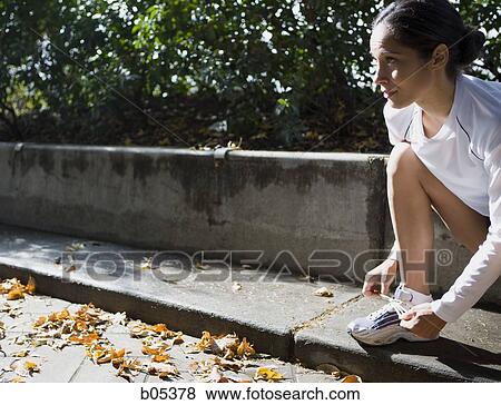 Female jogger tying shoelaces View Large Photo Image Stock Photo - Female jogger tying shoelaces. Fotosearch