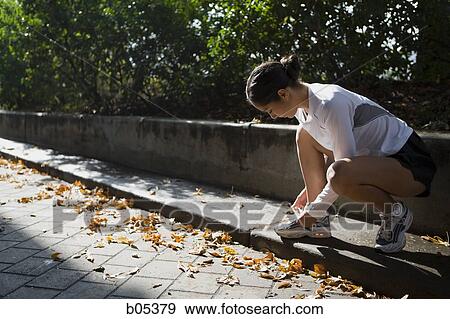 Female jogger tying shoelaces View Large Photo Image Stock Photo - Female jogger tying shoelaces. Fotosearch