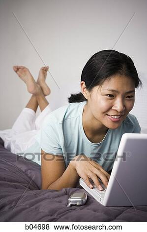 Female on bed with laptop and cell phone View Large Photo Image Stock Photo - Female on bed with laptop and cell phone. Fotosearch
