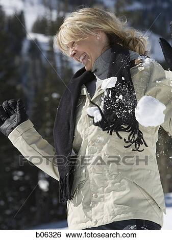 Stock Photograph - Female outside being hit with a snowball. Fotosearch