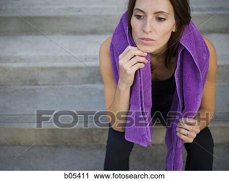 Stock Image - Female sitting on steps with towel outdoors. Fotosearch
